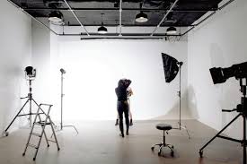Photography studio hire showing a model posing with studio lighting, backdrop, and indoor plants in a professional photo studio setup